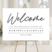 Custom minimalist rehearsal dinner welcome sign featuring the couple’s names and date, displayed on an easel at the event entrance.