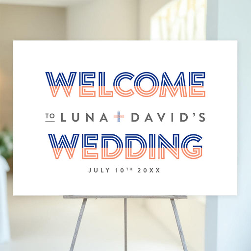 Modern wedding welcome sign with orange and blue striped accents and minimalist typography displayed on an easel.