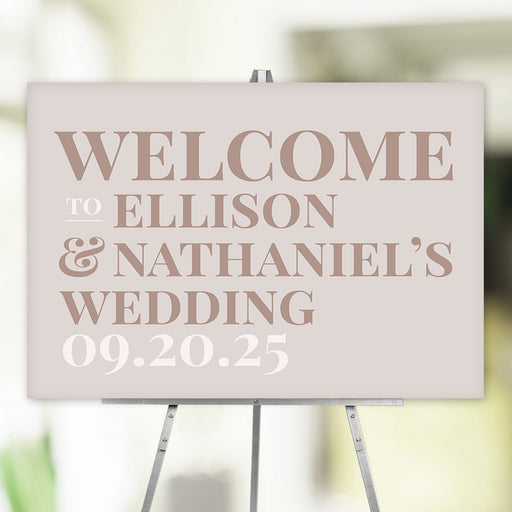 Wedding welcome sign with customized details in neutral colors and modern typography, displayed on an easel for ceremony or reception décor.