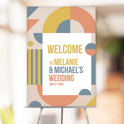 Custom geometric wedding welcome sign with personalized names and date, featuring abstract shapes in mustard, coral, and blue.