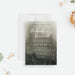 moody botanical wedding invitation with soft watercolor background, white script lettering, and delicate foliage details along the bottom-front