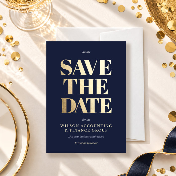 Navy blue save the date card with large gold lettering and company event details, styled with a white envelope and gold table decorations.
