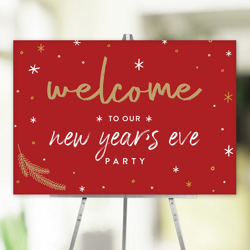 Red New Year’s Eve party welcome sign with gold and white lettering, festive stars, and pine branch accents, ideal decor for holiday celebrations.