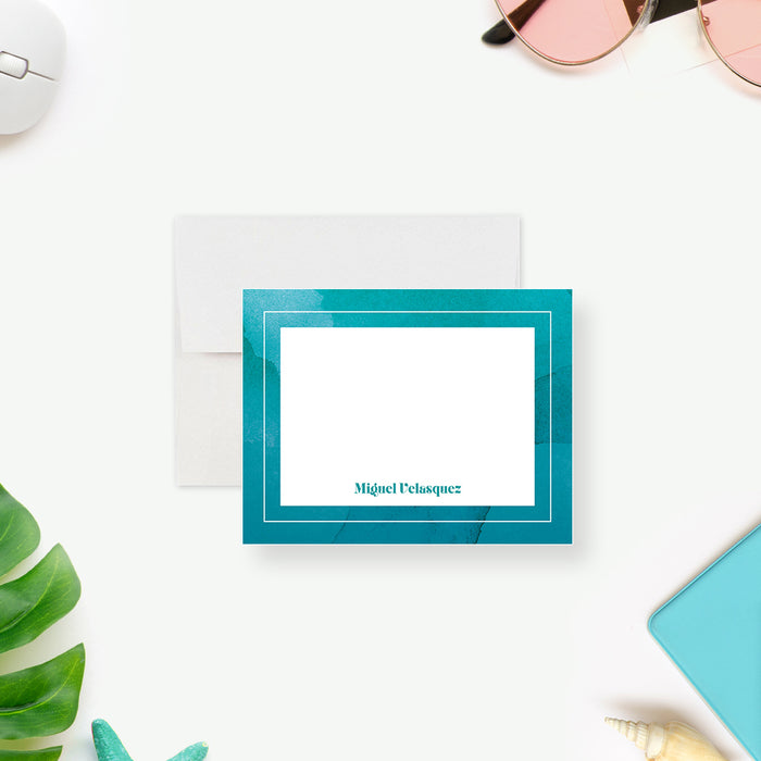 Personalized note card with a white front with layered aqua watercolor borders and a personalized name. Shown with a white envelope.