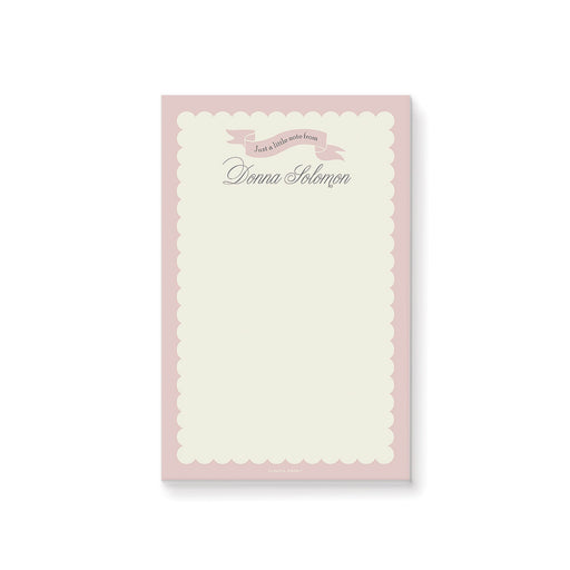 Blush pink custom notepad with pastel cream border and ribbon banner, featuring a personalized name for stationery gift or party favor.