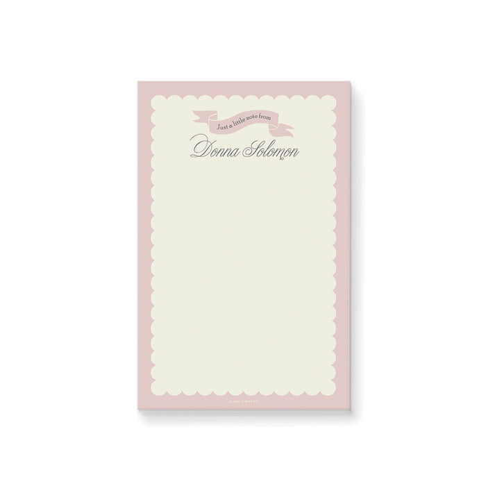 Blush pink custom notepad with pastel cream border and ribbon banner, featuring a personalized name for stationery gift or party favor.