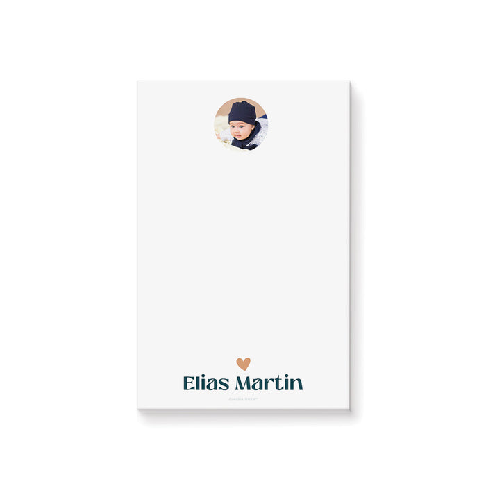 Personalized white baby photo notepad with a circular portrait, peach heart and child’s name in teal lettering