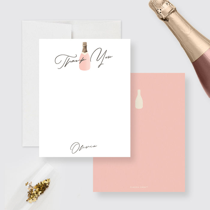Champagne thank you cards with a blush bottle and personalized script wording on the white front, and a cream bottle on a peach pink back.
