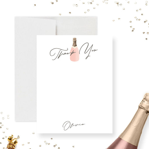 Personalized bachelorette thank you card with a blush champagne bottle, printed gold bottle top, black script wording and a name on a white front.
