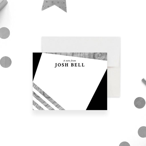 Personalized note card with a white front with black angular corners, printed silver stripes, and a name at the top. Shown with a white envelope.