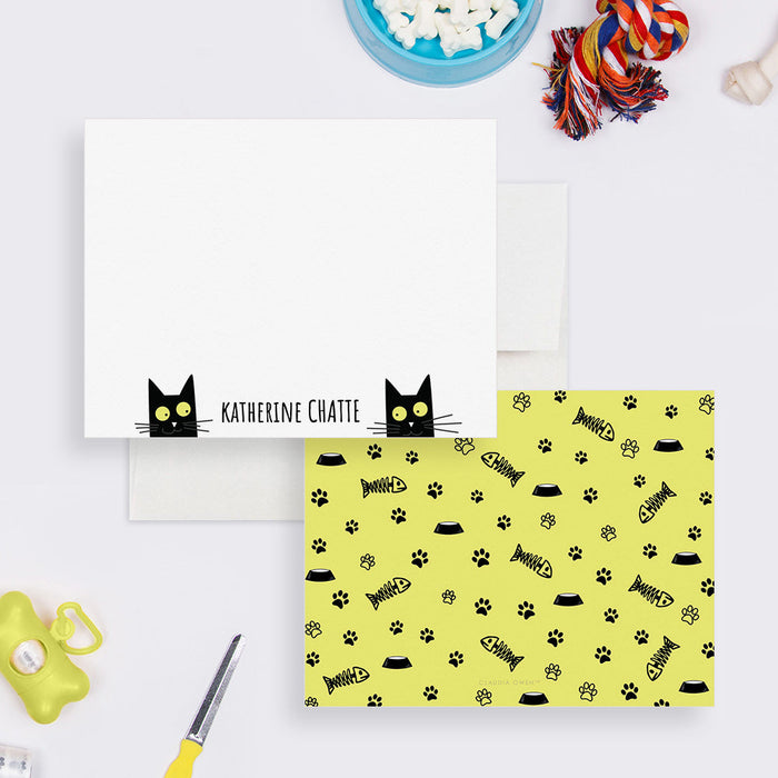 Front and back of personalized note cards with two black cat faces and a personalized name and a yellow back patterned with cat paws, fish bones and bowls.