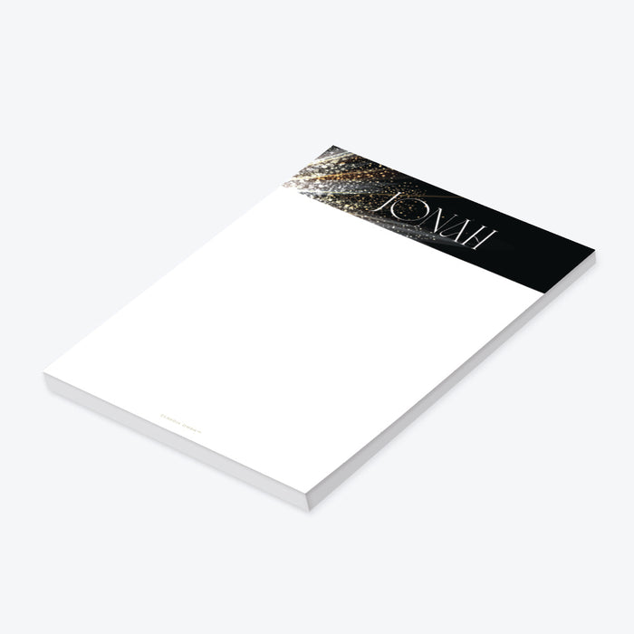Personalized corporate gala notepad with a black header, sparkling gold accents, custom name, and a blank white writing area.