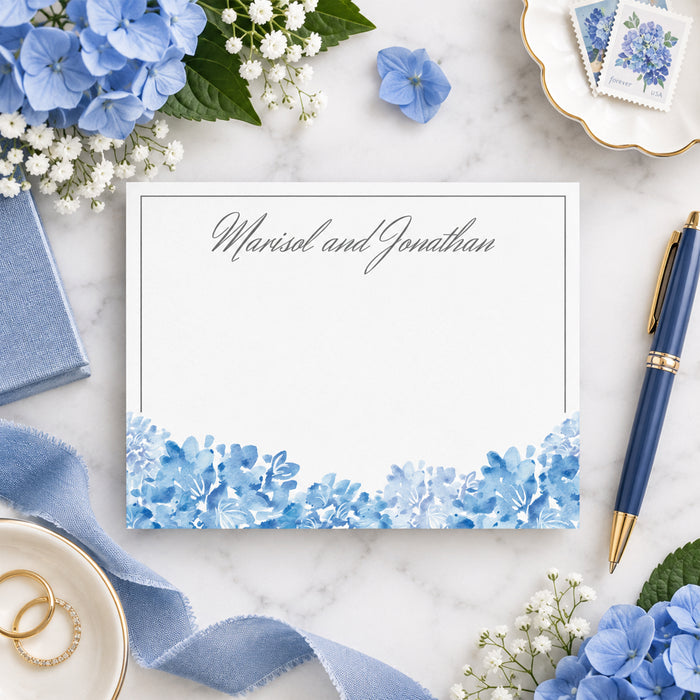 Personalized blue watercolor hydrangea wedding note card with couple’s names in gray script, a thin border, and blue flowers along the bottom