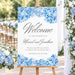 Personalized blue watercolor hydrangea wedding welcome sign with gray script lettering, couple’s names, wedding date, and floral borders displayed on an easel