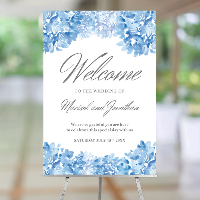Personalized blue watercolor hydrangea wedding welcome sign with gray script lettering, couple’s names, wedding date, and floral borders displayed on an easel