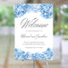 Personalized blue watercolor hydrangea wedding welcome sign with gray script lettering, couple’s names, wedding date, and floral borders displayed on an easel