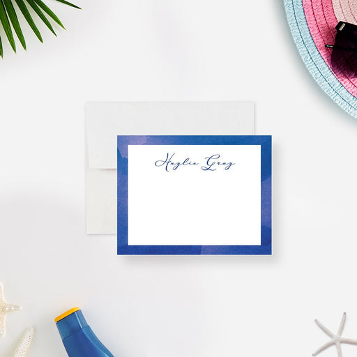 Personalized note card with a white writing area with a blue watercolor border and a name in script. Shown with a white envelope.