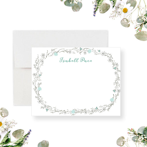 Personalized note card with a white front with a delicate botanical border and a personalized name in pale blue-green script. Shown with a white envelope.