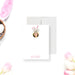 Personalized note card with a white front with a round photo, floral bunny ears, and a name in pink script. Shown with a white envelope.