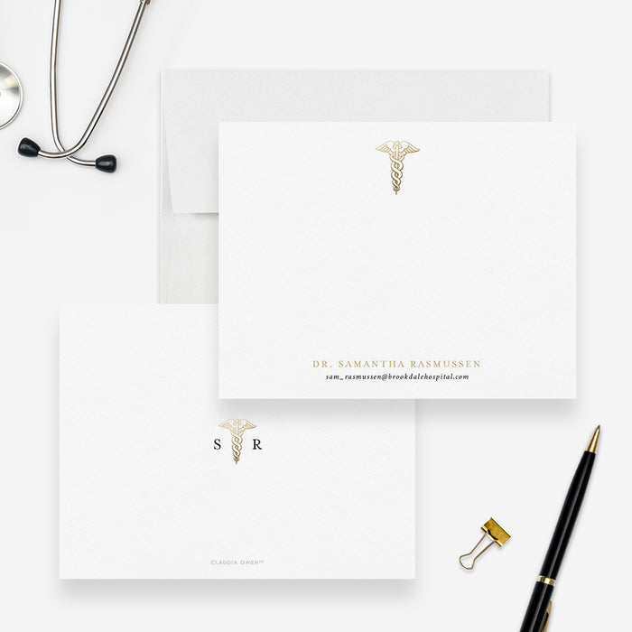 Personalized caduceus note cards with a printed gold medical symbol and name, shown with white envelopes-front-back