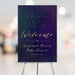 Personalized celestial baby shower welcome sign on an easel with a stroller constellation against a navy and purple starry sky