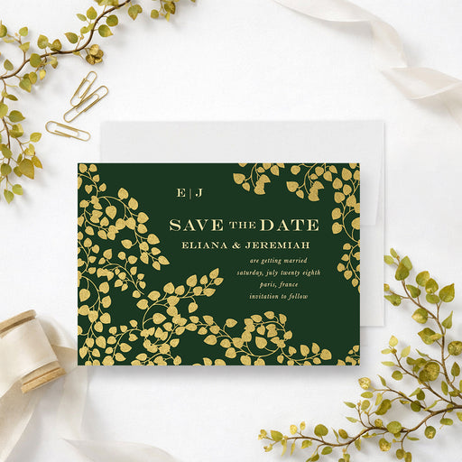 Personalized emerald green wedding save the date card with gold-colored leaf vines, couple’s monogram, names, wedding date and location-front