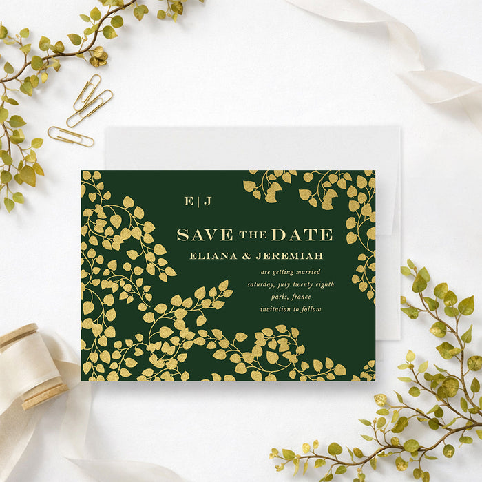 Personalized emerald green wedding save the date card with gold-colored leaf vines, couple’s monogram, names, wedding date and location-front