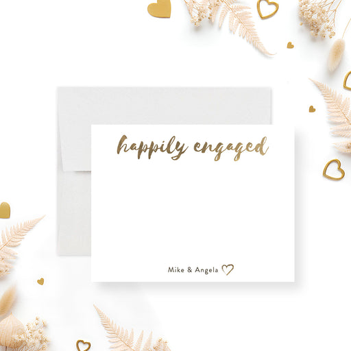 Front and back of personalized engagement note card with Happily Engaged script, couple’s names, beige back and gold heart accents-front