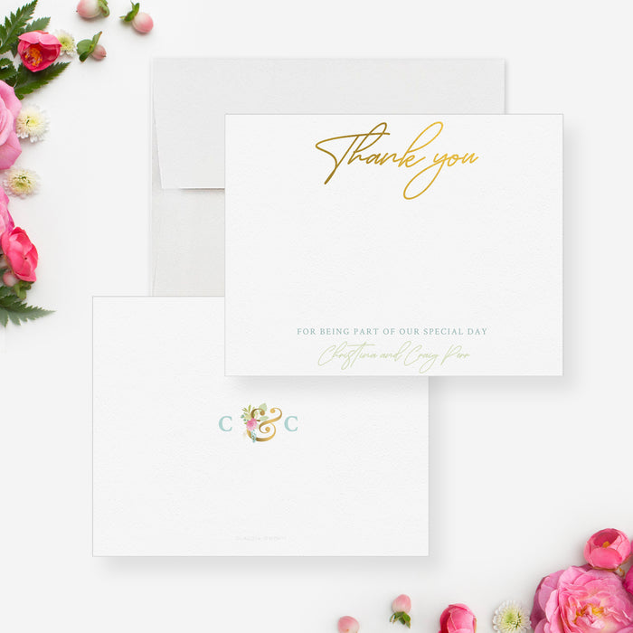 White wedding thank you note card with gold-colored script, beside a matching back with floral initials and an ampersand.