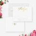 White wedding thank you note card with gold-colored script, beside a matching back with floral initials and an ampersand.