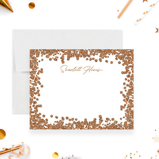 Personalized note card with a white front with a printed gold confetti border and a name in warm gold script. Shown with a white envelope.