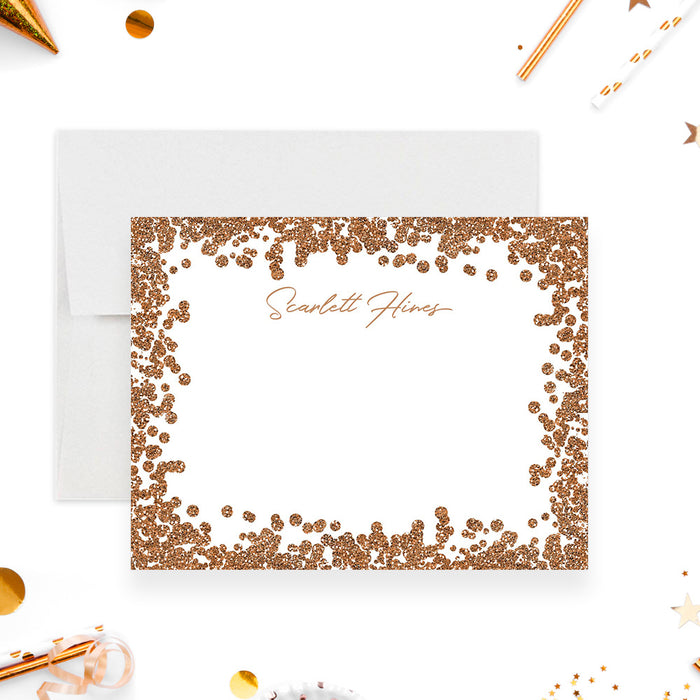 Personalized note card with a white front with a printed gold confetti border and a name in warm gold script. Shown with a white envelope.