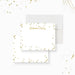 Personalized note card with a white front with scattered printed gold confetti and a name in script. Shown with a white envelope.