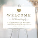 Personalized white wedding welcome sign with elegant gold lettering, a gold heart, couple’s names and wedding date
