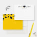 White personalized graduation note card with a black cap and class year, beside a yellow back decorated with black graduation caps.