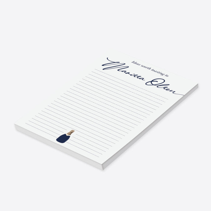 personalized navy champagne notepad with custom name in script, lined writing space, and small champagne bottle illustration-side