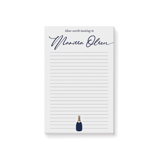 personalized navy champagne notepad with custom name in script, lined writing space, and small champagne bottle illustration