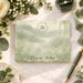 Personalized wedding note card with leafy monogram wreath, Emma and Michael names, misty sage watercolor landscape and delicate wildflowers-front