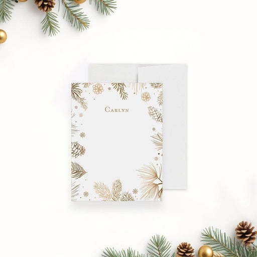 personalized holiday note card with gold-toned pine branches, pinecones, snowflakes, festive border, and custom name-front
