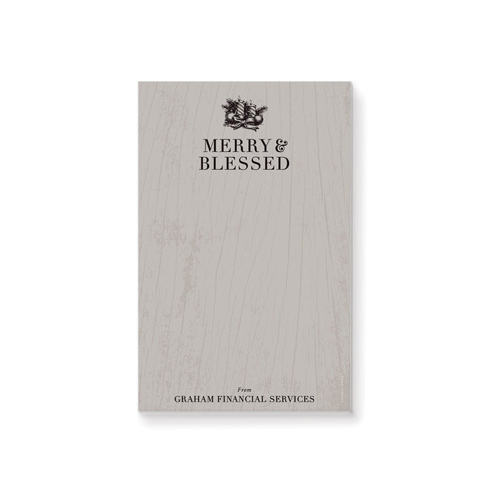 Personalized holiday notepad featuring “Merry and Blessed” text with wood grain, pine boughs, ornaments, ribbon, and candle illustrations. 