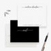 Black and white personalized note card with script name and address line, shown with a white envelope and pen-front-back