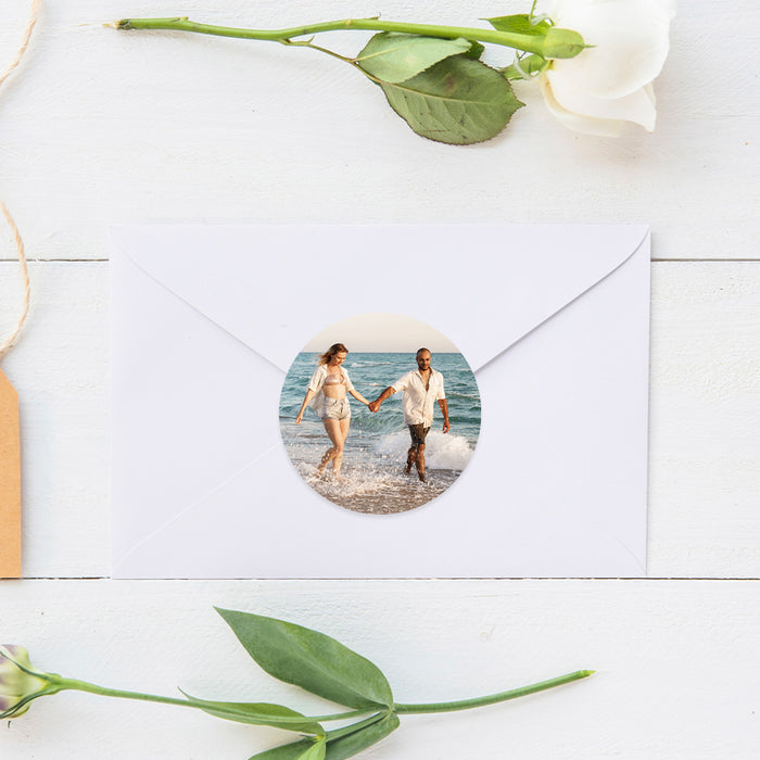 Envelope with a circular photo sticker of two people holding hands on a beach