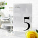 Table number card with '5' on a table setting with flowers and glasses.