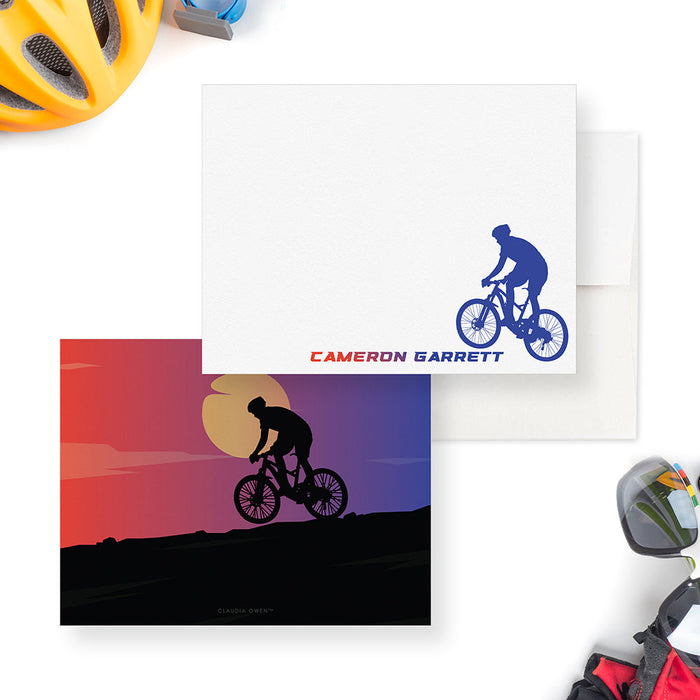 Front and back of personalized note cards with a blue mountain biker illustration and a personalized name and a sunset scene with a mountain biker silhouette on the back.