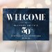 Personalized 50th birthday welcome sign with dark navy blue watercolor background, white modern lettering, honoree’s name, and celebration date