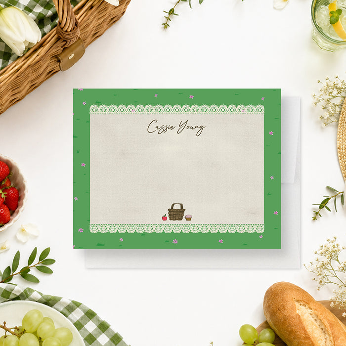 personalized picnic thank you card with custom name, lace border, green grass pattern, tiny pink flowers, and picnic basket illustration-front