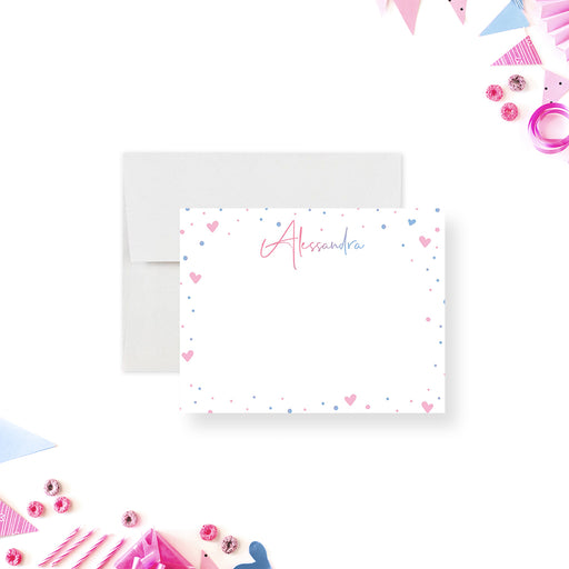 Personalized white note card with a pink script name and a border of small pink and blue hearts and confetti.