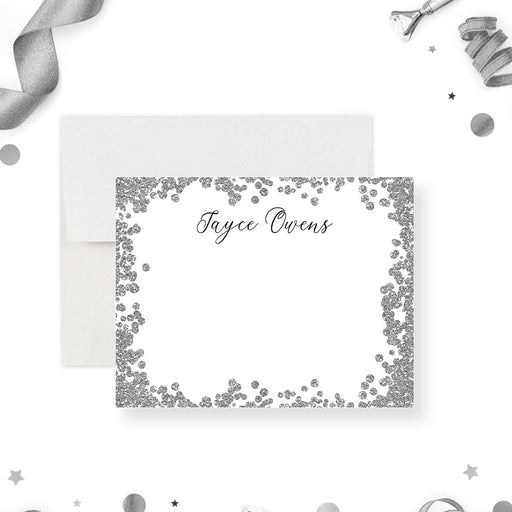 Personalized note card with a white front with a printed silver confetti border and a name in black script. Shown with a white envelope.