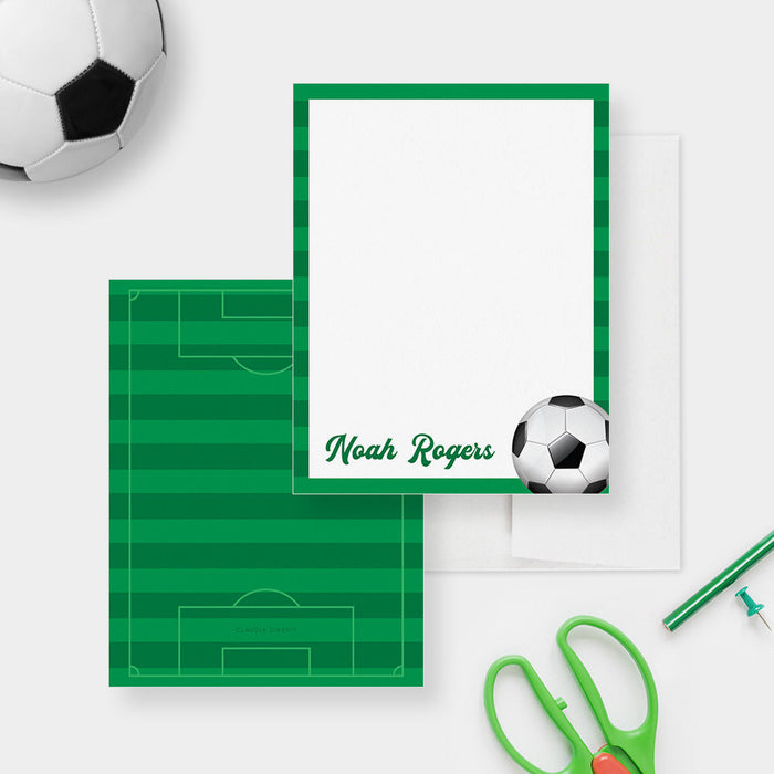 Front and back of personalized note cards with a soccer ball, green frame and a personalized name and a green soccer field patterned back.