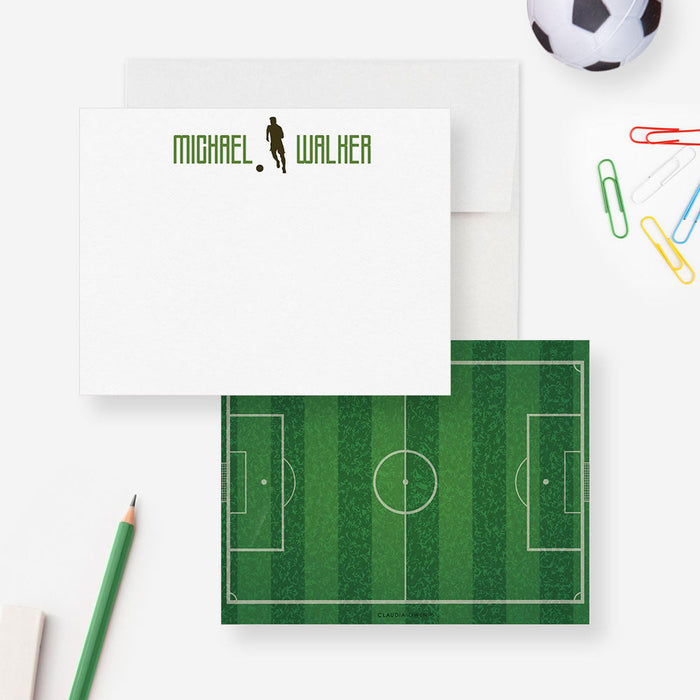 Front and back of personalized note cards with a soccer player silhouette and a personalized name in green and a green soccer field patterned back.